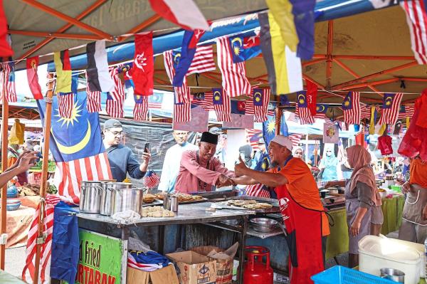 Thumbs up: Mohamad Haizan (left) greeting a vendor during a campaign walkabout at the Kampung Melayu morning market in Kluang. — Bernama
